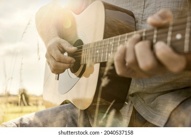 Guitarist Playing Acoustic Guitar Outside In A Field In The Summer Sunshine