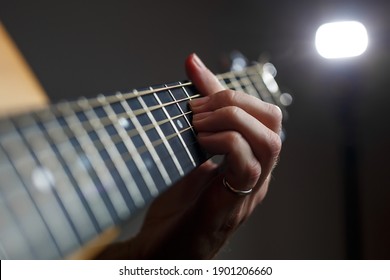 Guitarist playing a chord on a guitar fretboard close up