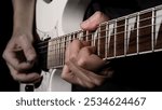 Guitarist Playing Guitar In Studio. Low key of man hand play white electric guitar for songs and cover music or skill practice. Close up of musician playing guitars instrument against black background