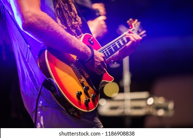 Guitarist playing on electric bass guitar on stage. Colorful, soft focus and blur background. - Powered by Shutterstock