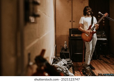 Guitarist recording in studio music HD photo. artist playing music in a studio. Man with long hair playing guitar and recording. Recording session in studio with artist playing guitar. - Powered by Shutterstock