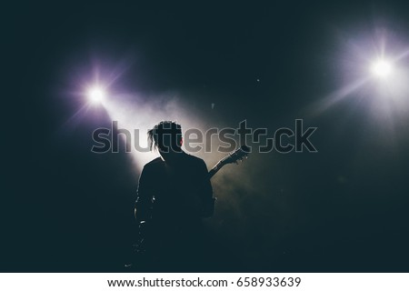 Guitarist silhouette on a stage in a backlights playing rock music
