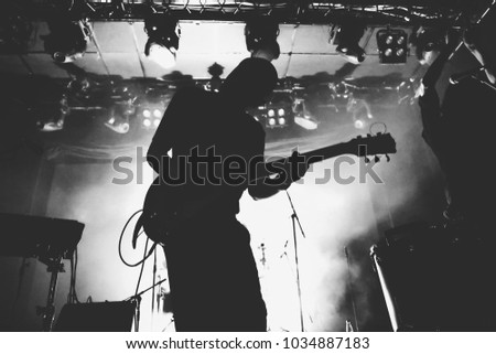 Guitarist silhouette on a stage in a bright stage lights. Black and white