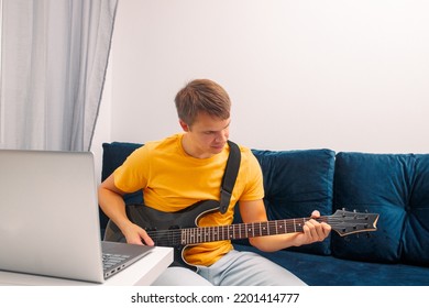 Guitarist Is Watching A Virtual Video Tutorial At Home. Hobby. Man Learn To Play Guitar Online.  The Guy Is Sitting At Home On The Sofa And Watching An Online Lesson, Learning To Play The Guitar.