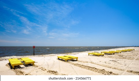 Gulf coast beach in Gulfport, Mississippi with lounge chairs along the shoreline.