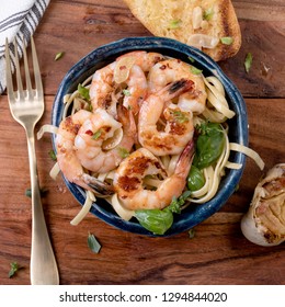 Gulf Coast Jumbo Shrimp In A Blue Blow On A Wood Table With Pasta And Gold Fork Garlic Bread 