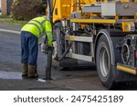 Gully sewer drain jet cleaning: Municipal Medium Volume Combination (MVC) Tanker Truck operative uses vacuum suction pipe in Suburban Street