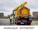 Gully sewer drain jet cleaning: Municipal Medium Volume Combination (MVC) Tanker Truck operative uses vacuum suction pipe in Suburban Street