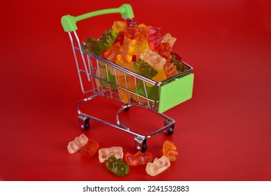 Los osos caramelos en una pequeña cesta de un supermercado sobre un fondo rojo.	