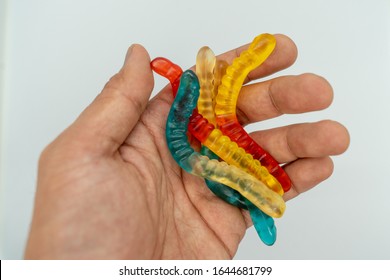 Gummy Worms On Hand In A White Background. 