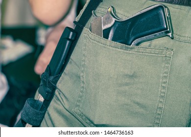 Gun in the back pocket of greenish trousers