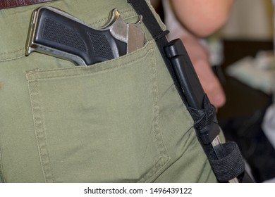 Gun in the back pocket of greenish trousers