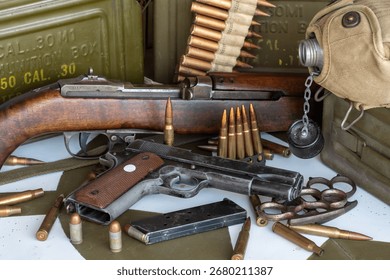 Gun and a box of bullets are on a table. The gun is a Colt 45. There are many bullets scattered around the gun