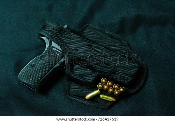 A
Gun in holster gun and bullet on black background.

