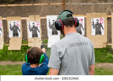 Gun instructor teaching young kid how to shoot from firearm at shooting range