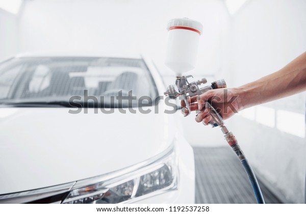 gun with
paint in the hands of a man to paint a
car.