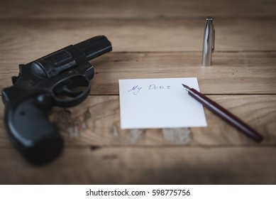 Gun and pen with sheet of paper on the table. Vintage effect, background.