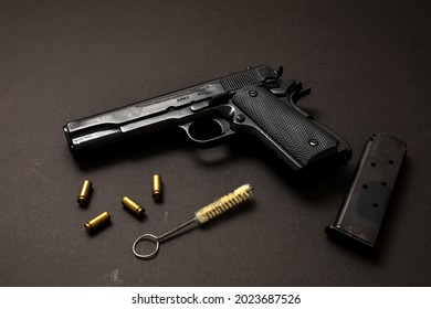 Gun pistol 9mm, magazine, ammo bullet shells and cleaning rod on black background. Black metal weapon maintenance, automatic handgun for military and security concept. Side view
