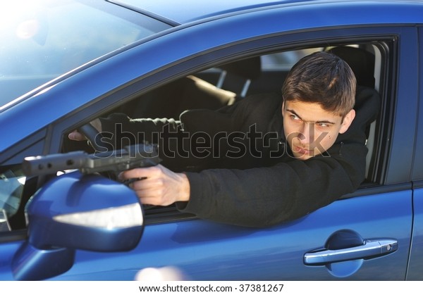 Gunman in car holding\
gun with silencer