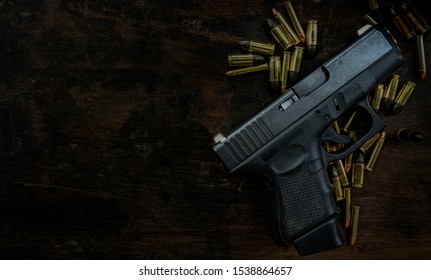 Guns And Ammunition Placed In A Wooden Table,Short Guns And Ammunition Placed On A Black Background Table,Guns And Ammunition Are Ready To Use. Noisy Weapon