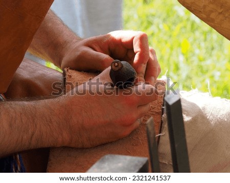 The gunsmith makes flint plates for the bolt of medieval firearms, hands and tools in close-up. Historical reconstruction of a military camp.