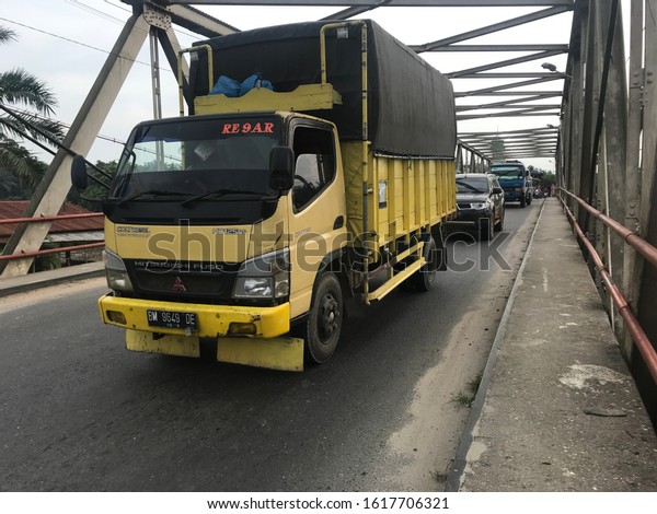Gunting Saga,\
North Sumatra/Indonesia -January 13,2020 : a colt diesel truck\
carrying goods across the\
bridge