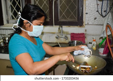 Gurgaon, India 2020: Girl Cooking At Home During Lockdown. She Is Wearing Face Mask To Protect Herself Fro Corona Virus Pandemic. Citizen Are Advised To Follow Social Distancing And Stay At Home 