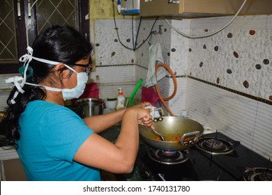 Gurgaon, India 2020: Girl Cooking At Home During Lockdown. She Is Wearing Face Mask To Protect Herself Fro Corona Virus Pandemic. Citizen Are Advised To Follow Social Distancing And Stay At Home 