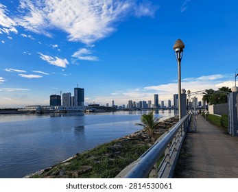 Gurney Bridge, an important link between Gurney Drive, and the small town in the Andaman Islands. City skyline reflects in calm waters below. Modern buildings stretch behind gentle clouds. Walking path invites quiet strolls beside metal railings.
