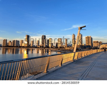 Gurney Bridge, an important link between Gurney Drive, and the small town in the Andaman Islands. City skyline reflects in calm waters below. Modern buildings stretch behind gentle clouds. Walking path invites quiet strolls beside metal railings.