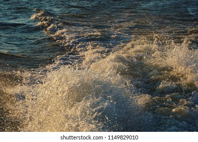 Gushing flowing turbulent water splashing and churning in a beautiful and powerful display of physics.  Fantastic beauty in surge of power on top of the vast body of water.  Sun reflecting is great  - Powered by Shutterstock