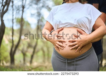 Gut of pregnant woman being held by her hands in nature