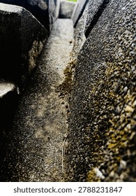 The gutter between the wall and the walkway.