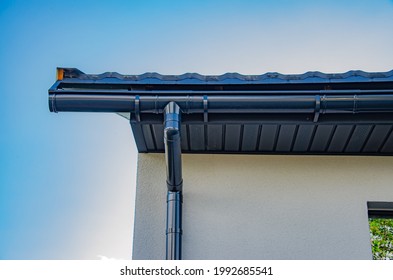 Gutter with downpipe on the roof a house.