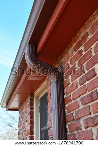 Gutter downspout on the eave of a brick house