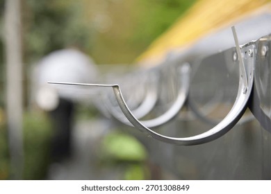 Guttering: Galvanised hooks, or brackets fixed to a newly installed PVC fascia on roof under renovation. 