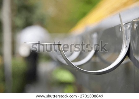 Guttering: Galvanised hooks, or brackets fixed to a newly installed PVC fascia on roof under renovation. 