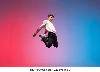 guy acrobat doing back fat in new lighting, male dancer jumps and falls in the air on red blue background, hiphop performer does trick and levitates in the air