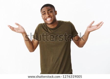 Guy apologizing for now knowing about b-day. Confused awkward good-looking african american male shrugging with hands raised near shoulders smiling silly with sorry look as unaware or clueless