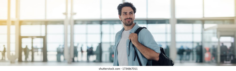 The Guy With The Backpack At The Airport. Young Handsome Man Waiting For Boarding, Walks Through Airport Terminal