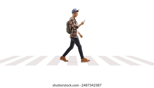Guy with a backpack and cap walking and looking at mobile phone at a pedestrian crossing isolated on white background