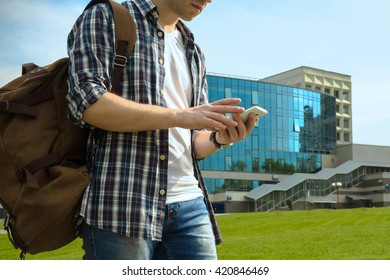 Guy With Bag Is Looking For Something In Smartphone On The Station Background