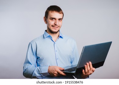 A Guy In A Blue Shirt Holds A Laptop On A White Background. Male Office Worker.