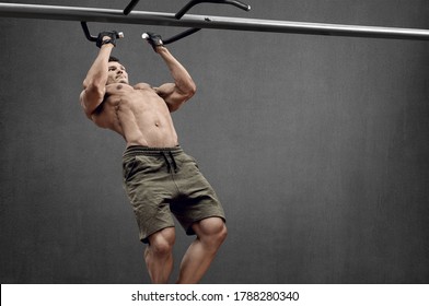 Guy bodybuilder perform exercise do chin-ups, horizontal bar on grey wall background with empty space for text. Gym concept - Powered by Shutterstock