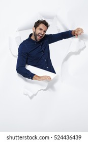 Guy Breaking Free From White Paper In Studio