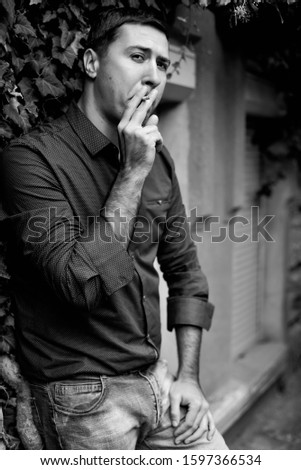 Similar – young guy in a shirt smokes on the street