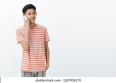 Guy Calling Friend Talking Casually Via Smartphone Standing To Left Side Of Copy Space Gazing Aside With Nice Smile Using Cellphone To Connect With Family While Living Abroad Over White Wall