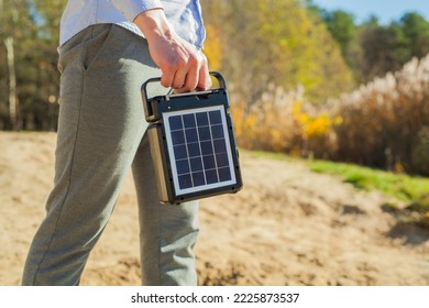 The guy is carrying a portable solar charging station in his hands. Eco-friendly energy for camping and outdoor recreation. Solar panel with battery