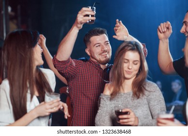 Guy Is In Center Of Attention. Happy People Dancing In The Luxury Night Club Together With Different Drinks In Their Hands.