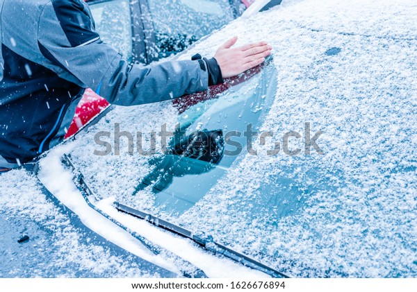 Guy clean\
car windshield covered with snow and\
ice